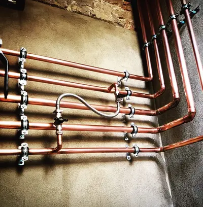 Réseau de tuyaux en cuivre fixés au mur, avec vannes et raccords